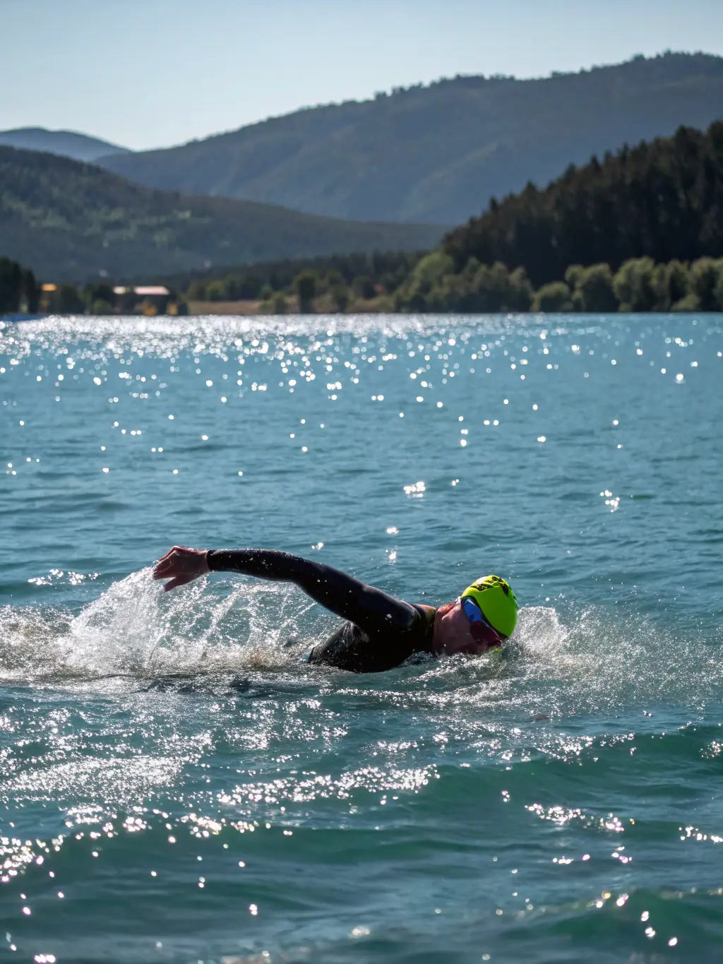 A diverse group of athletes participating in a triathlon training session, focusing on swimming techniques in a clear blue lake, under the guidance of experienced coaches.